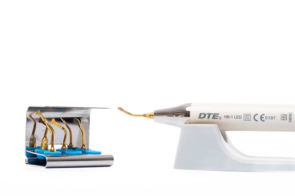 Close-up image of a dental-handled soldering iron with a metallic tip, positioned on a white plastic stand on the right side of the image. To the left, there is a set of five yellow-tipped soldering i